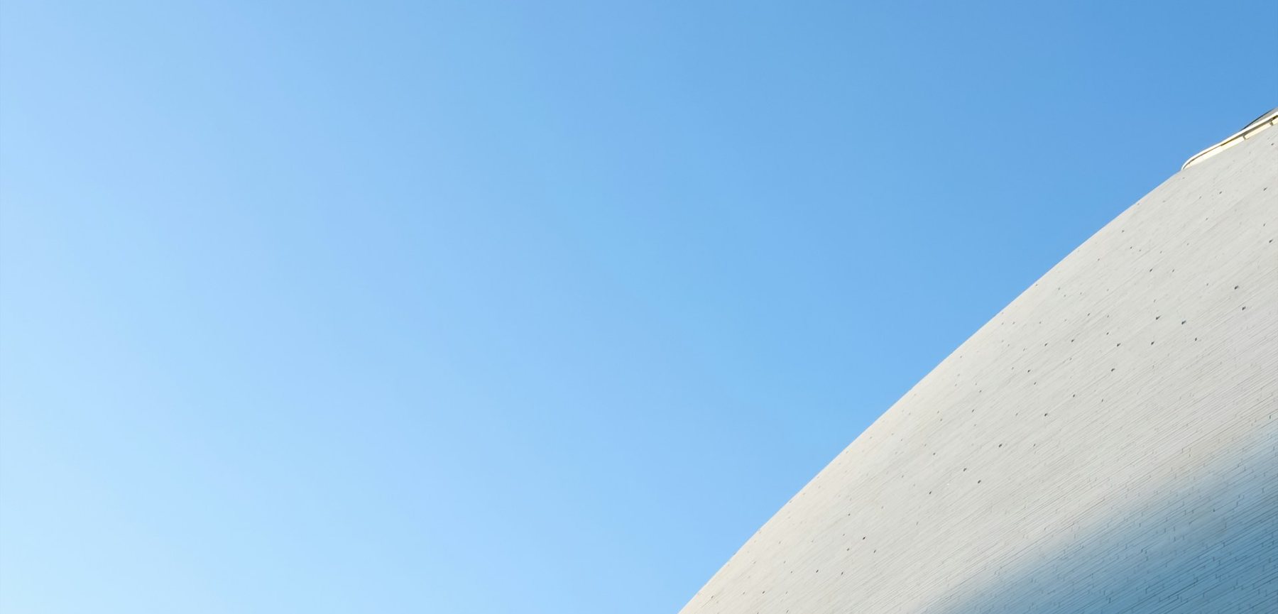 Pale curved façade rising into a clear morning sky